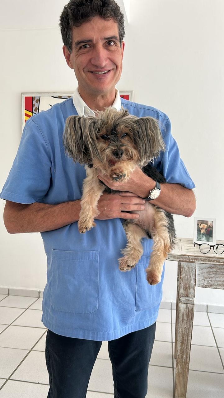Dr. Gustavo segurando um cachorro pequeno no colo