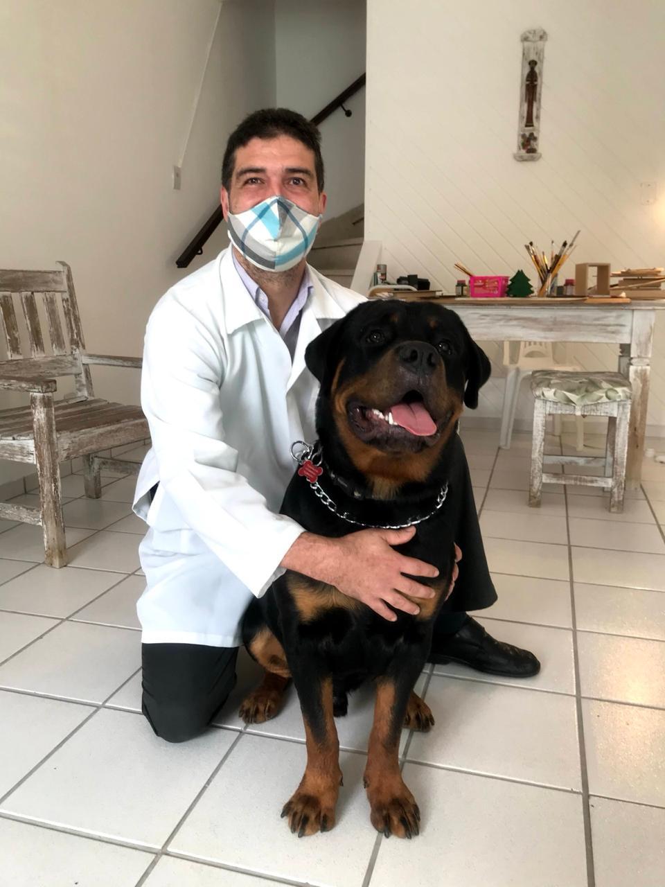 Dr. Gustavo ao lado de um Rottweiler durante atendimento